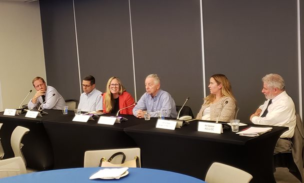 Men and women speak on a panel.